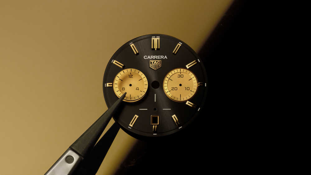 Cadran noir et or de la montre Tag Heuer Carrera porté par une minutieuse pince 